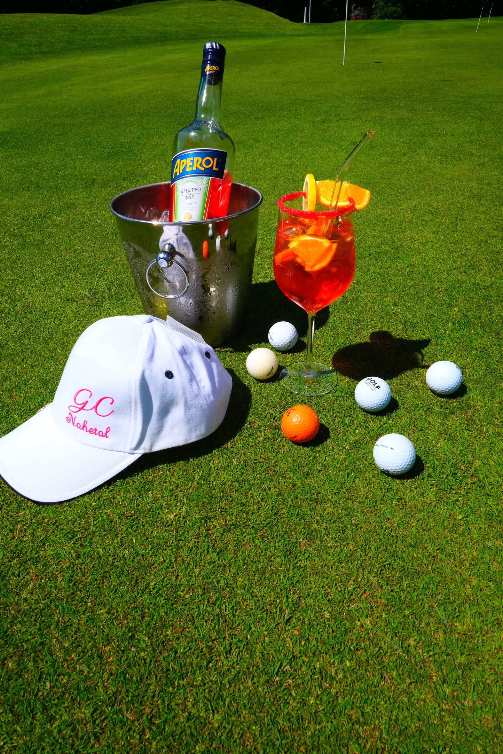 Flasche, Glas und Golfbälle auf dem Rasen