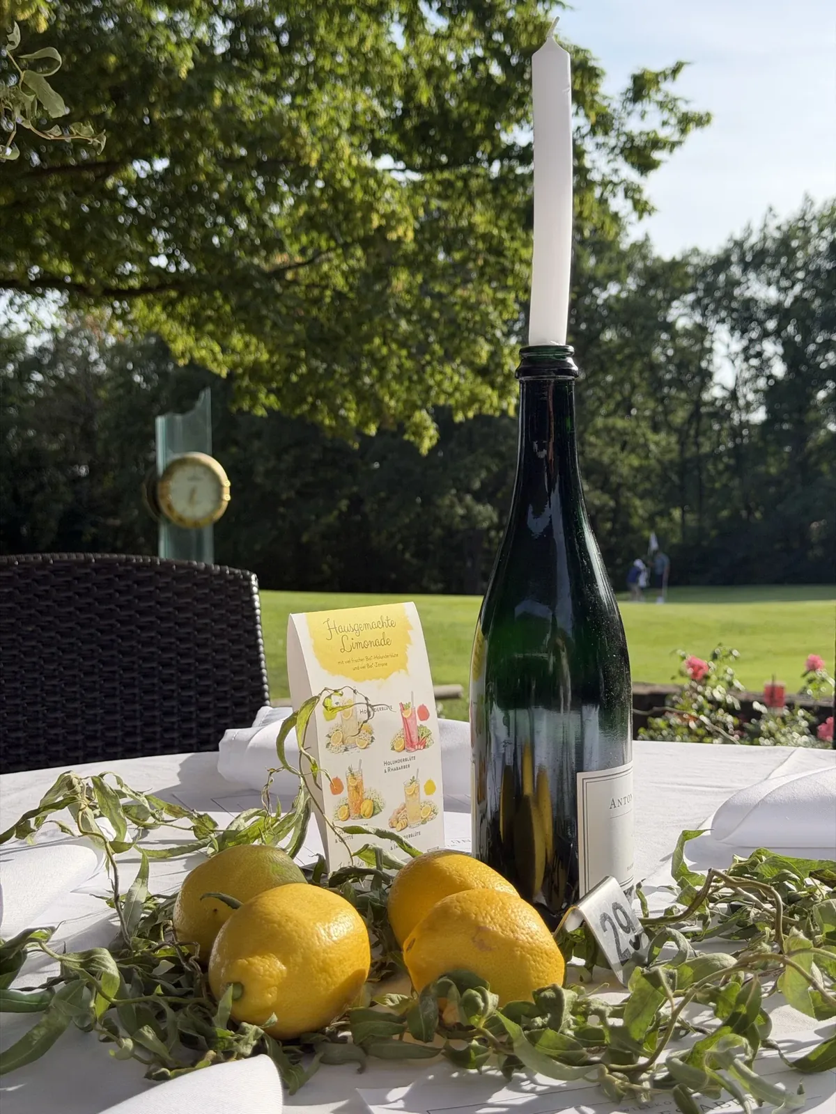 Weinflasche mit Kerze und Zitronen auf einem Terrassentisch